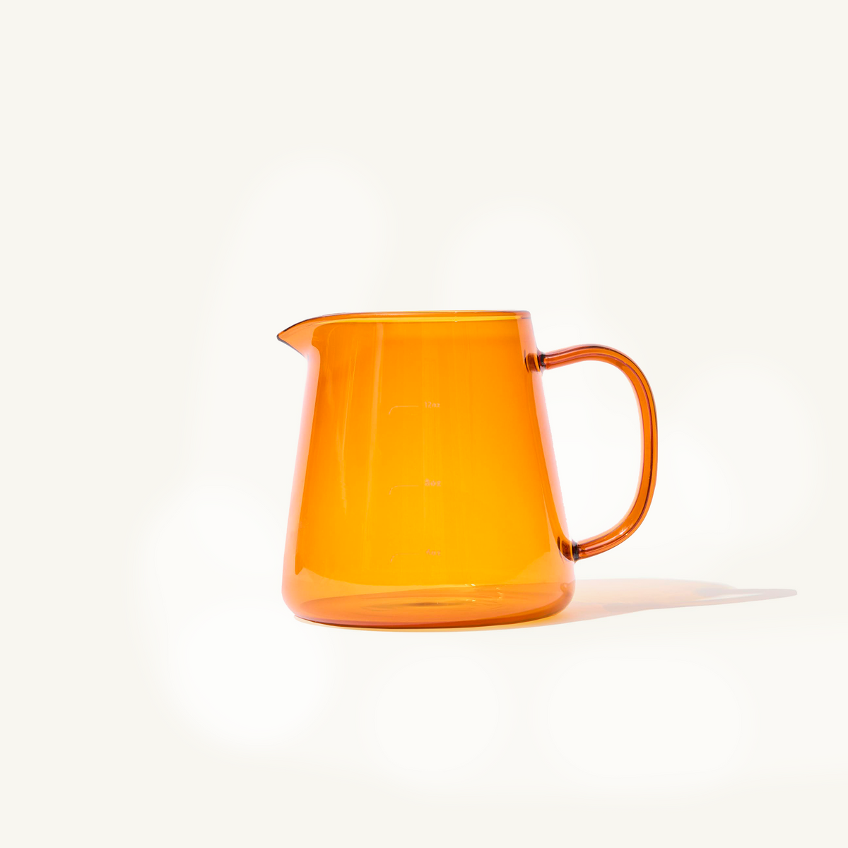 Amber Glass Pitcher for lattes on an off white background