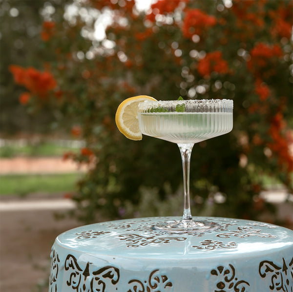 Cocktail with a lemon wedge on a decorative table outdoors