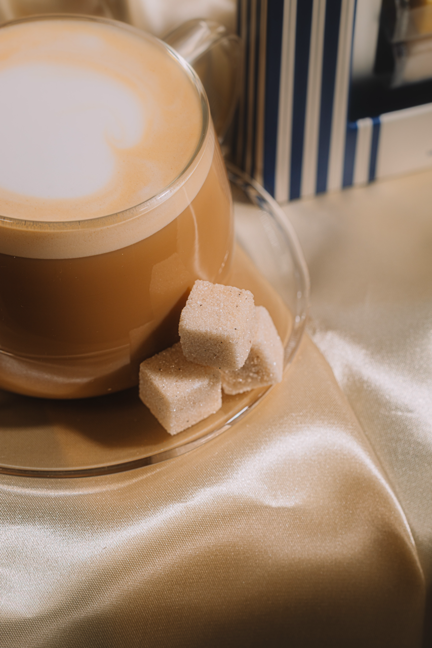 Cappuccino in a glass cup with three LUXE MIxer Cubes on a beige surface