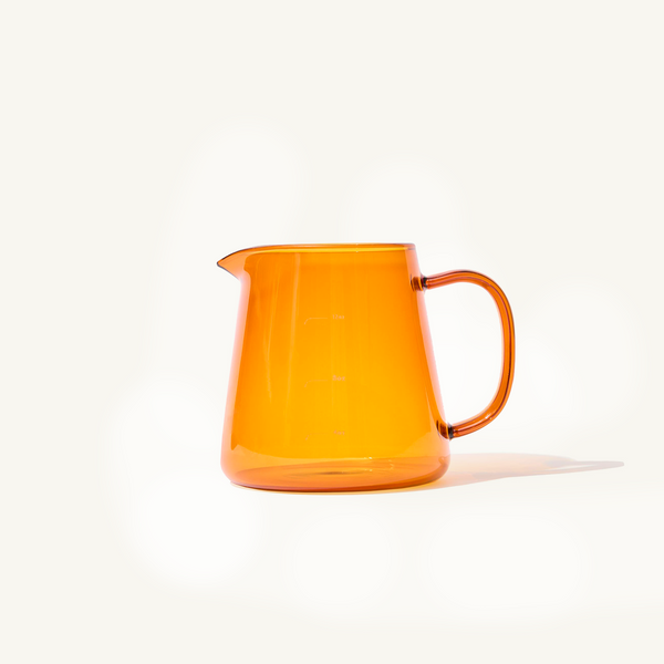 Amber Glass Pitcher for lattes on an off white background