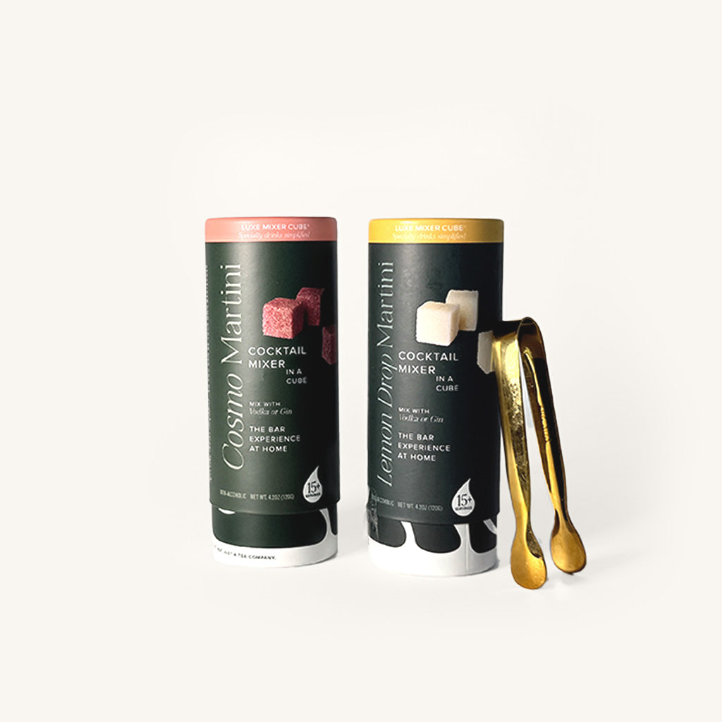 Cosmo and Lemon Drop Martini Tallboys in dark green cylindrical packaging on an off white background