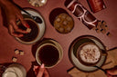 A flat lay of coffee drinks, including a cup of hot coffee, an iced drink with ice cubes, and a latte with cinnamon, alongside sugar cubes and a carton of flavored coffee.