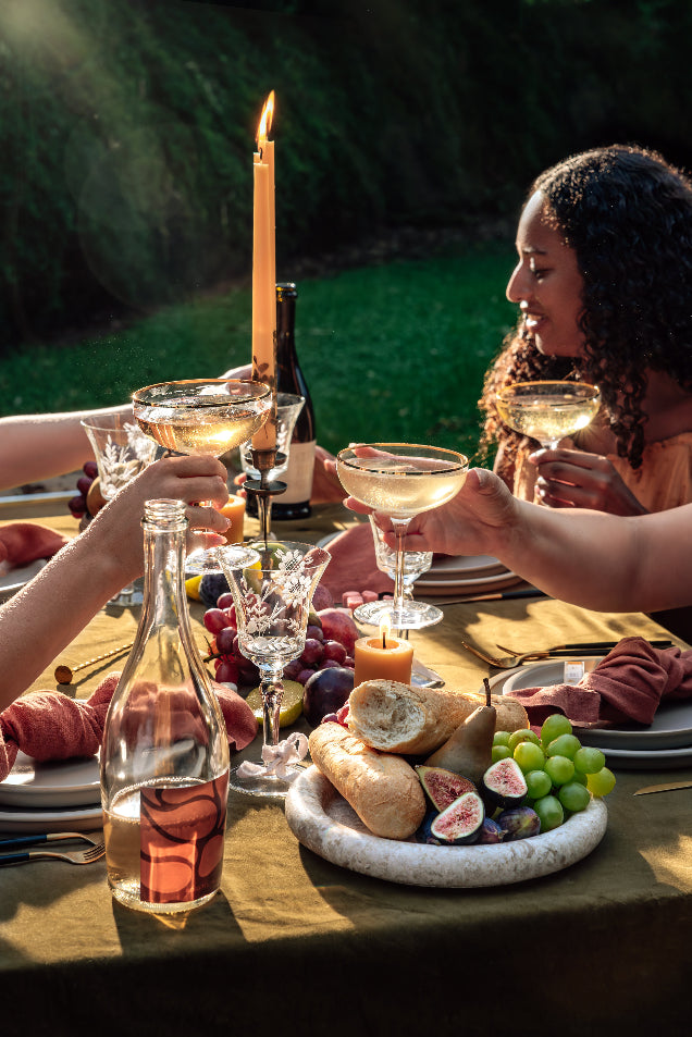 People enjoying a meal outdoors with wine glasses and food on a table.